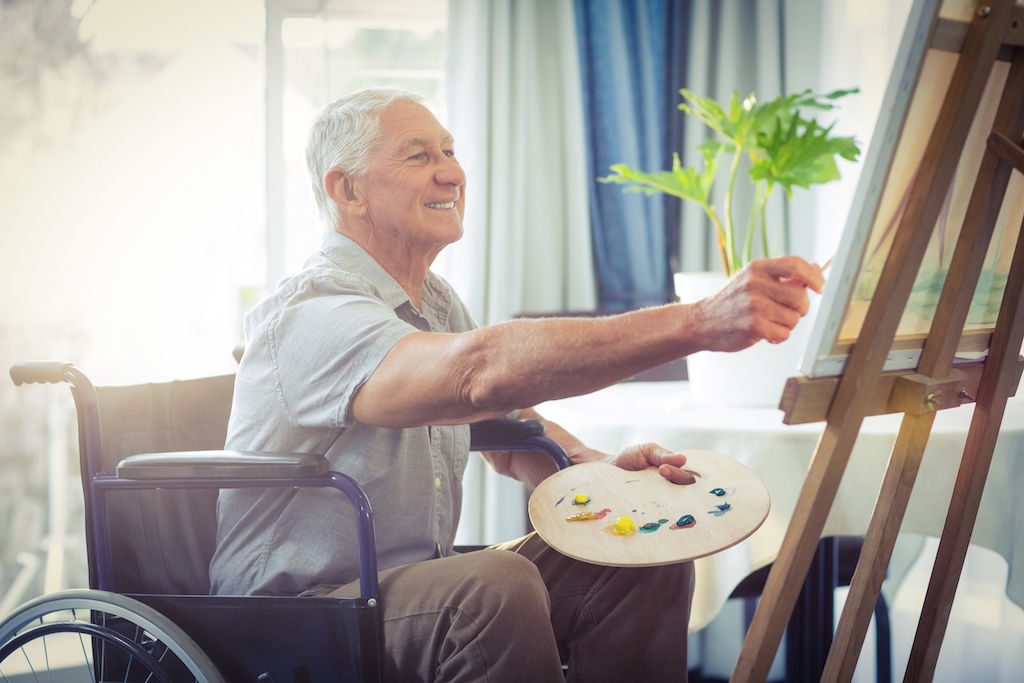 Man in wheelchair painting on easel